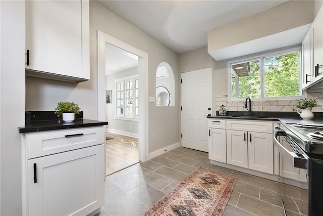 kitchen with a wealth of natural light, white cabinetry, sink, and stainless steel electric range