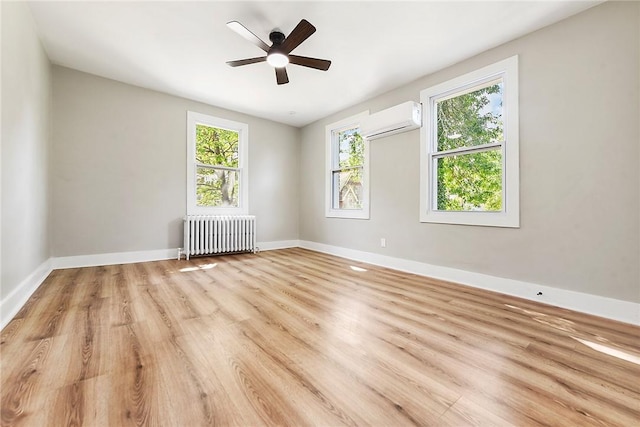 spare room featuring radiator, ceiling fan, a wall mounted AC, and light hardwood / wood-style floors