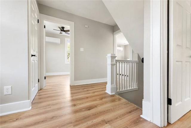 hallway with a wall unit AC and light wood-type flooring