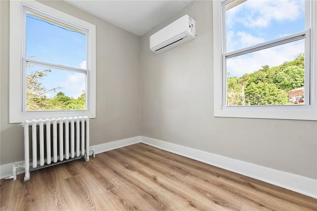 unfurnished room with wood-type flooring, radiator heating unit, and an AC wall unit