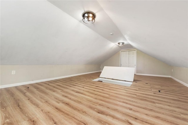 additional living space featuring light wood-type flooring and vaulted ceiling