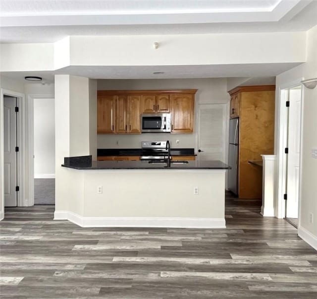 kitchen with sink, kitchen peninsula, stainless steel appliances, and dark wood-type flooring