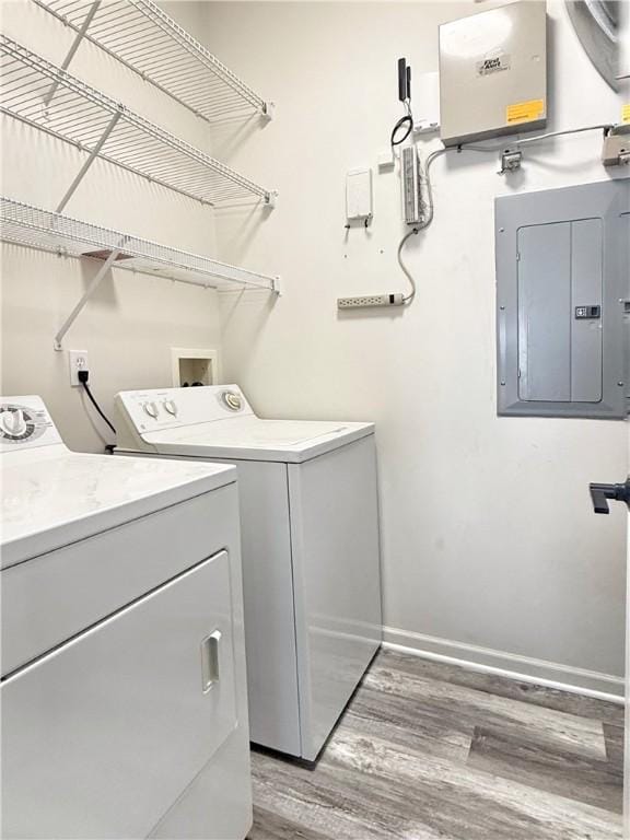 washroom with wood-type flooring, independent washer and dryer, and electric panel