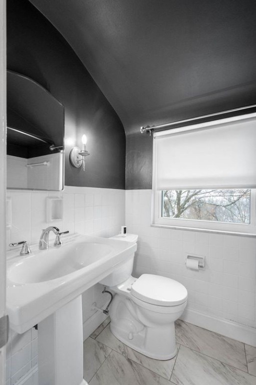 bathroom featuring toilet and tile walls