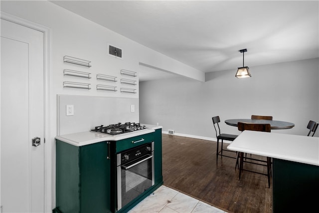 kitchen featuring green cabinetry, decorative light fixtures, and appliances with stainless steel finishes