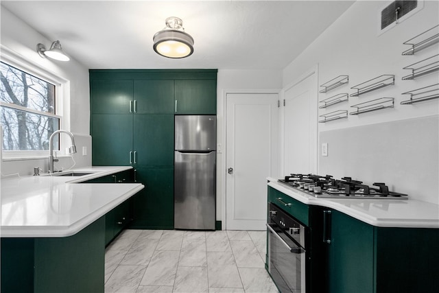 kitchen with kitchen peninsula, sink, green cabinets, and stainless steel appliances