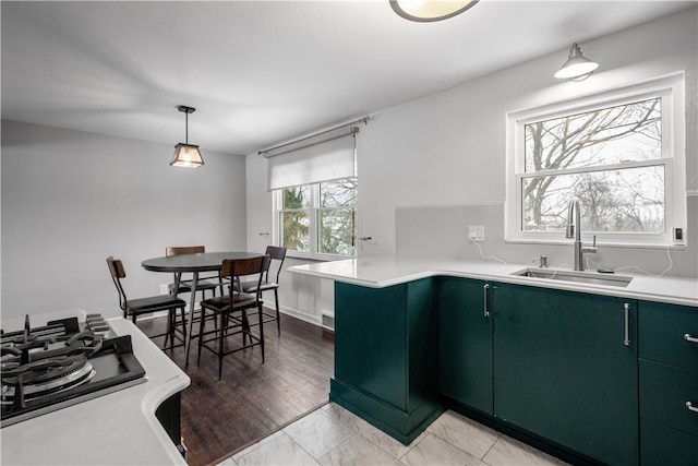 kitchen featuring green cabinets, sink, and pendant lighting