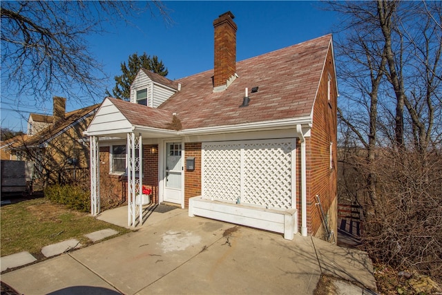 back of property with brick siding and a chimney