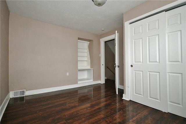 unfurnished bedroom featuring dark wood-type flooring and a closet