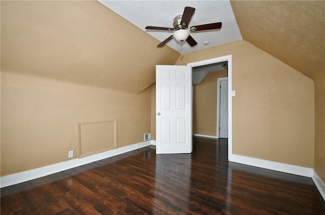 additional living space featuring a textured ceiling, ceiling fan, dark wood-type flooring, and vaulted ceiling