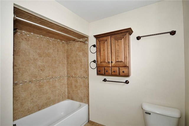 bathroom featuring tiled shower / bath combo and toilet