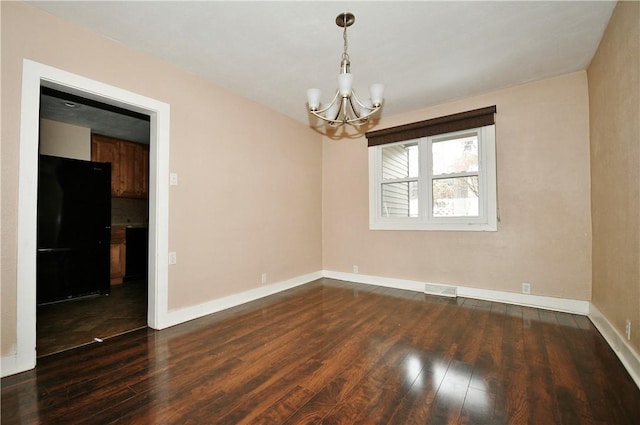 empty room featuring dark wood-type flooring and a chandelier