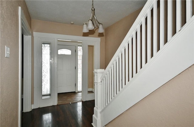 foyer with dark wood-type flooring, a chandelier, and a textured ceiling