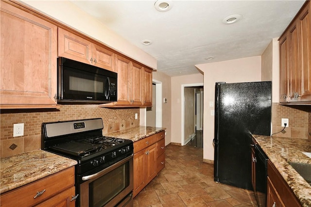 kitchen featuring light stone countertops, tasteful backsplash, and black appliances