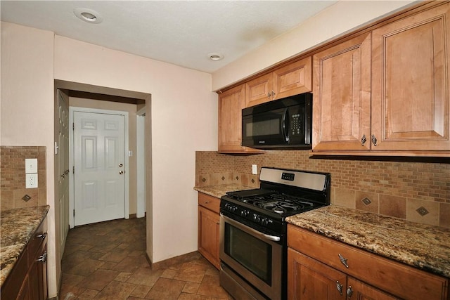 kitchen featuring stainless steel gas range oven, light stone countertops, and backsplash