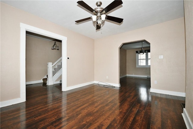 empty room featuring dark hardwood / wood-style flooring and ceiling fan with notable chandelier