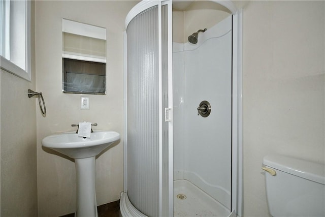 bathroom with toilet, a shower with door, and sink