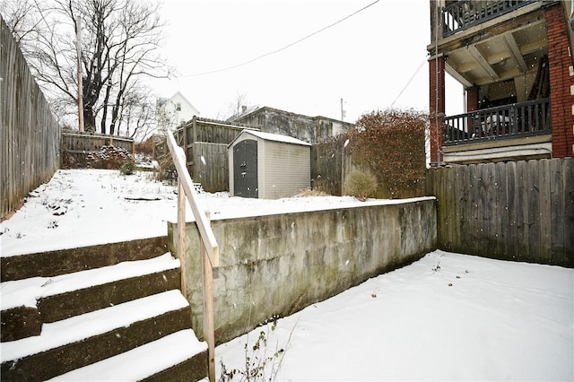 snowy yard featuring a shed