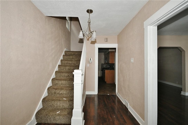 stairs with hardwood / wood-style flooring and a notable chandelier