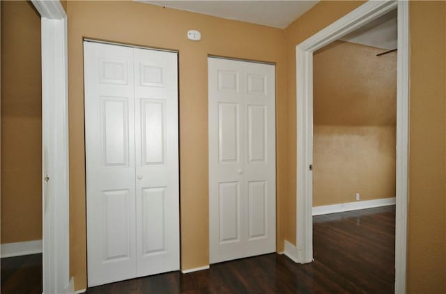 unfurnished bedroom featuring multiple closets and dark hardwood / wood-style floors