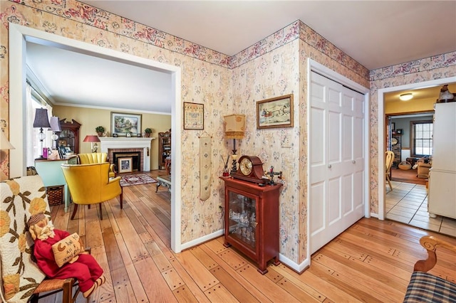 corridor with light hardwood / wood-style floors and crown molding