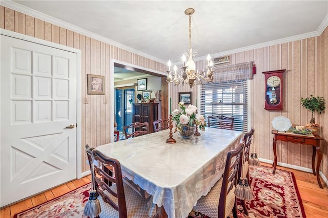 dining space featuring hardwood / wood-style floors, ornamental molding, and an inviting chandelier