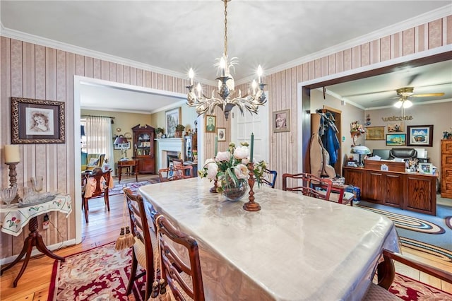 dining area featuring light wood-type flooring, ceiling fan with notable chandelier, and ornamental molding