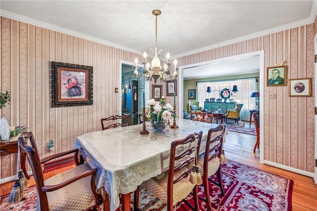 dining space with crown molding, hardwood / wood-style floors, and a notable chandelier