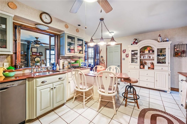 kitchen with dishwasher, light tile patterned floors, decorative light fixtures, and sink