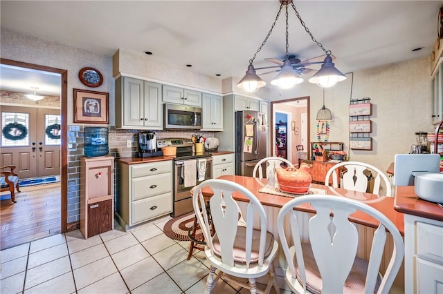 kitchen featuring ceiling fan, light tile patterned floors, decorative light fixtures, butcher block counters, and stainless steel appliances