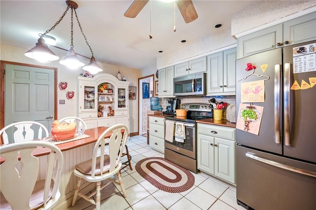 kitchen featuring wood counters, tasteful backsplash, stainless steel appliances, ceiling fan, and light tile patterned flooring