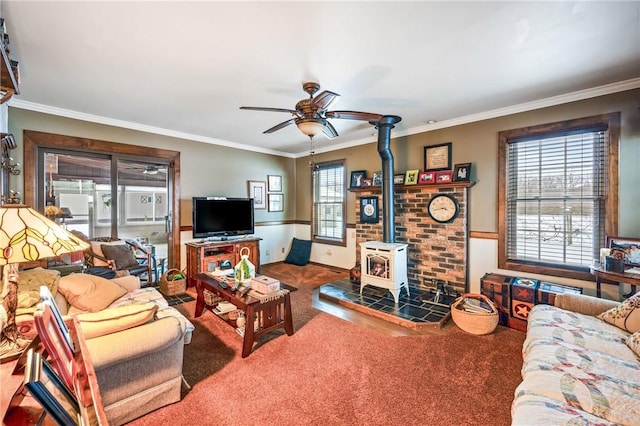 living room featuring ceiling fan, a wood stove, crown molding, and carpet floors