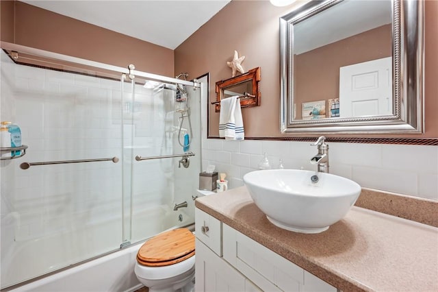 full bathroom with tasteful backsplash, bath / shower combo with glass door, vanity, tile walls, and toilet