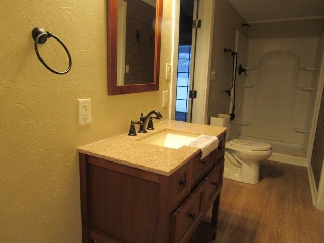 bathroom with toilet, vanity, wood-type flooring, and walk in shower