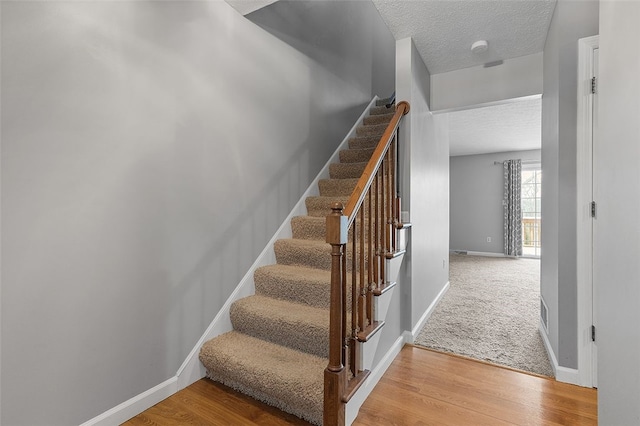 stairs with hardwood / wood-style floors and a textured ceiling