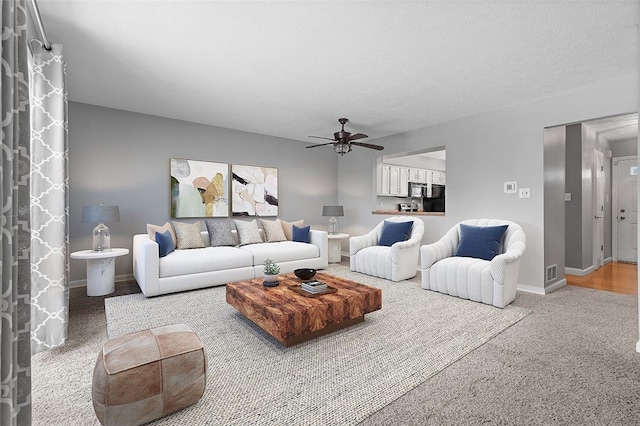 living room featuring ceiling fan and a textured ceiling