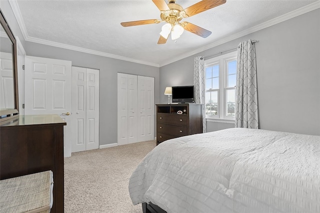 carpeted bedroom featuring a textured ceiling, ceiling fan, crown molding, and two closets