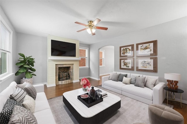 living room with hardwood / wood-style flooring, ceiling fan, and a large fireplace