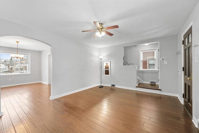 unfurnished living room featuring ceiling fan with notable chandelier and hardwood / wood-style flooring