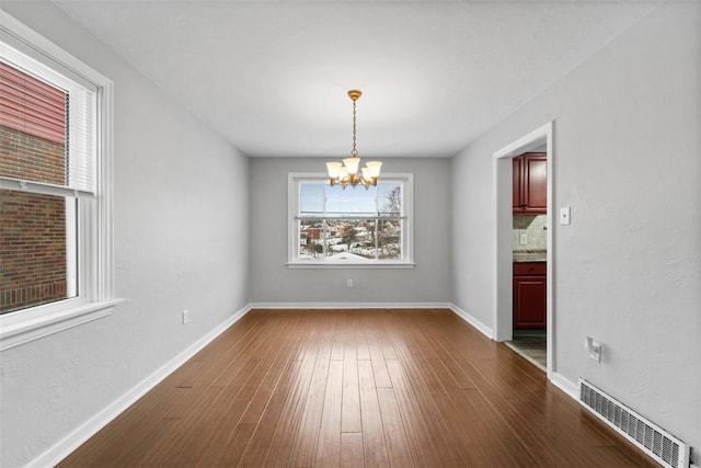 empty room featuring a chandelier and dark hardwood / wood-style floors