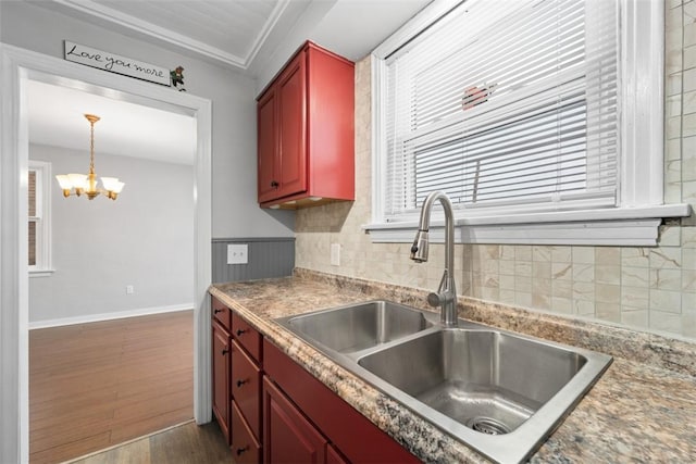 kitchen featuring dark wood-type flooring, sink, hanging light fixtures, decorative backsplash, and a chandelier