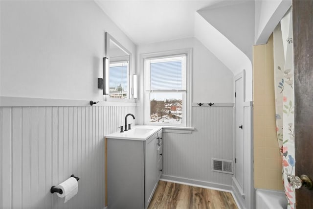 bathroom with hardwood / wood-style flooring, vanity, shower / bath combo, and vaulted ceiling