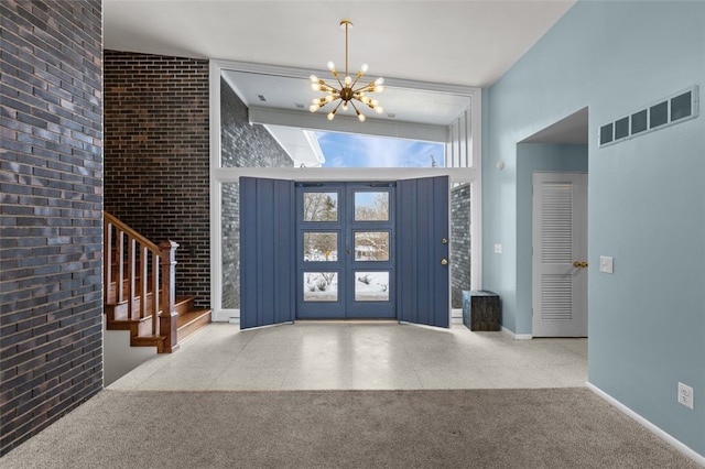 foyer entrance with french doors, vaulted ceiling, an inviting chandelier, and brick wall