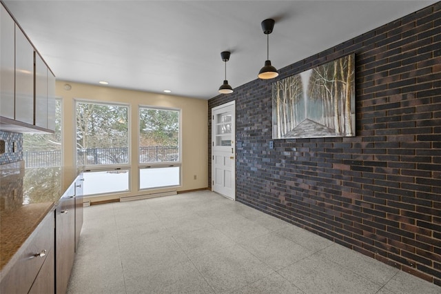 unfurnished living room featuring brick wall