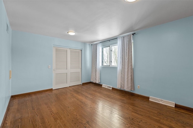 unfurnished bedroom with a closet and dark wood-type flooring