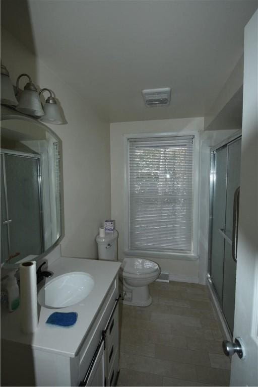 bathroom featuring vanity, toilet, and a shower with door