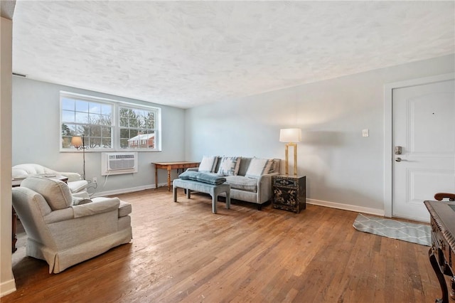 living room featuring hardwood / wood-style flooring, a wall unit AC, and a textured ceiling