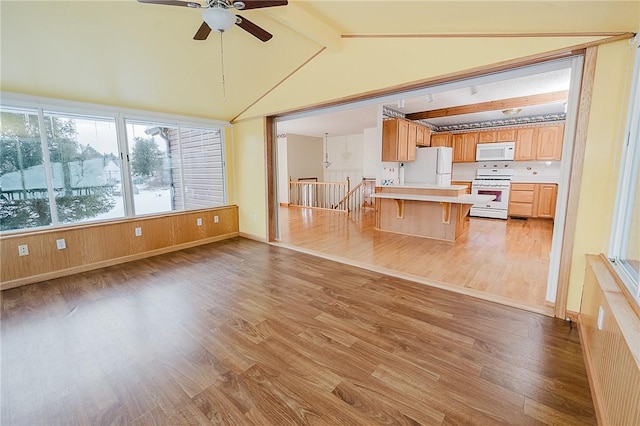 kitchen featuring a kitchen breakfast bar, white appliances, ceiling fan, light hardwood / wood-style flooring, and vaulted ceiling with beams