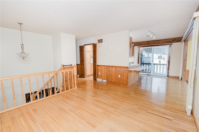 spare room with a textured ceiling, wooden walls, and light hardwood / wood-style flooring