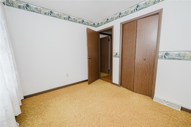 unfurnished bedroom with a closet and light colored carpet